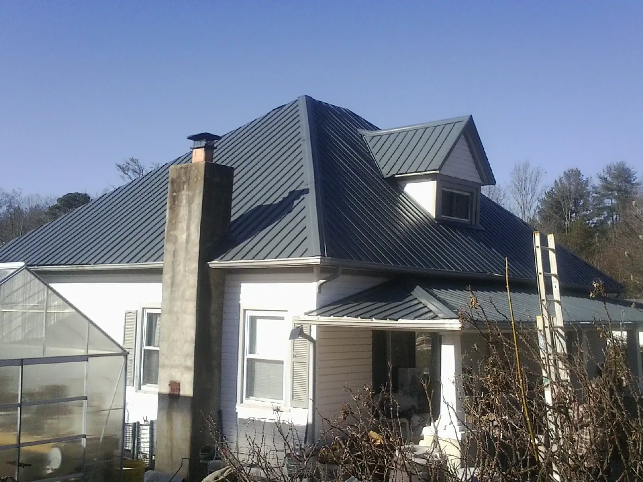Dark blue standing seam metal roof on a white farmhouse with dormer — Slate & Tile Roof Repair by Roofing Brothers in Bingen