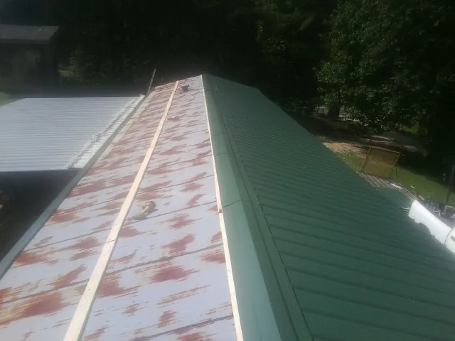 Old rusted panels beside newly installed green metal roofing — Wind Damage Roof Repair by Roofing Brothers in Bingen