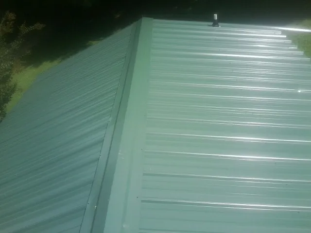New green metal panels meeting at the ridge of a roof — Flat Roof Repair work by our crew in Bingen