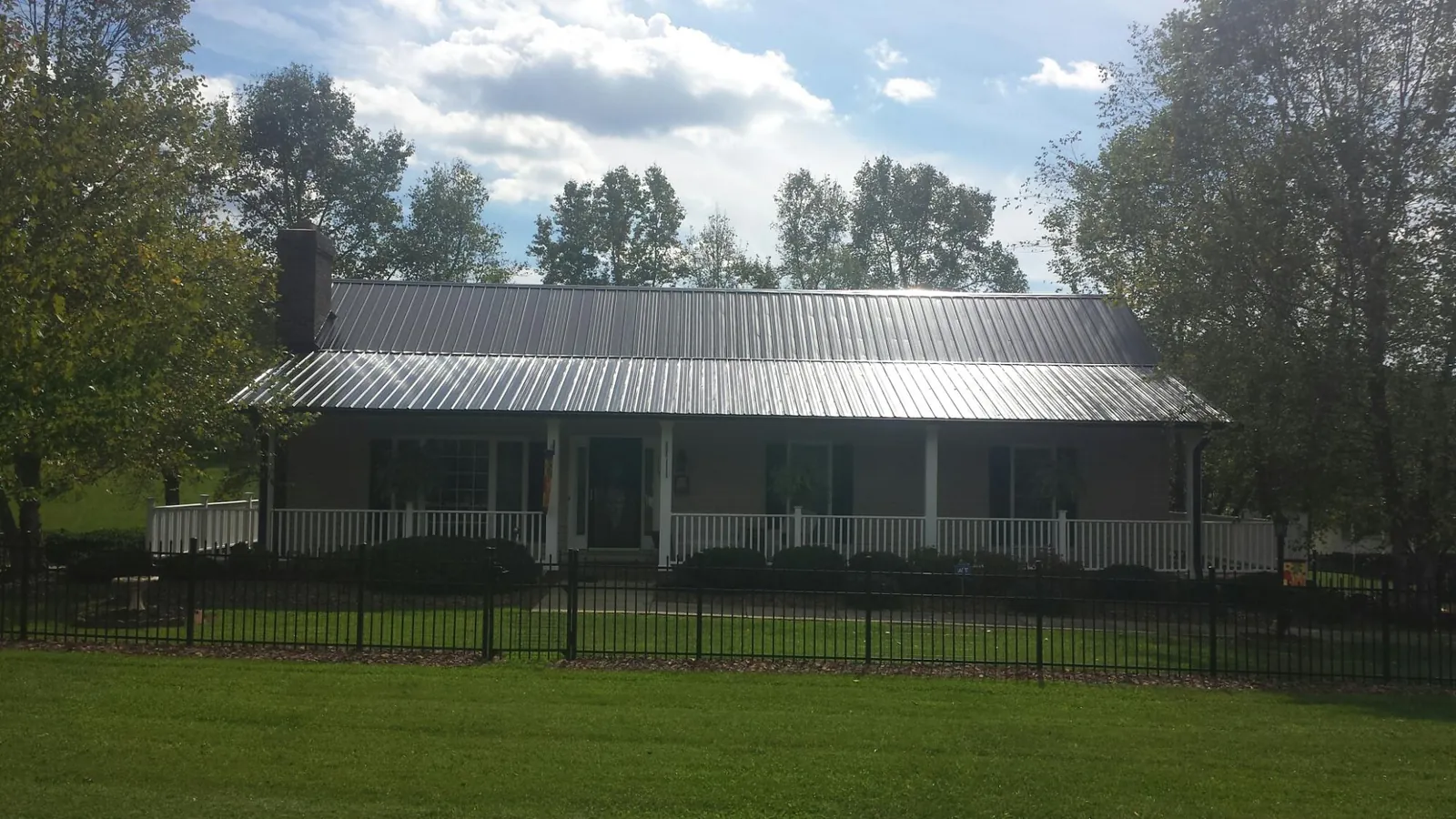 Gray metal roof on a brick ranch with a full width front porch — Gutter Guard Installation work by our crew in Bingen