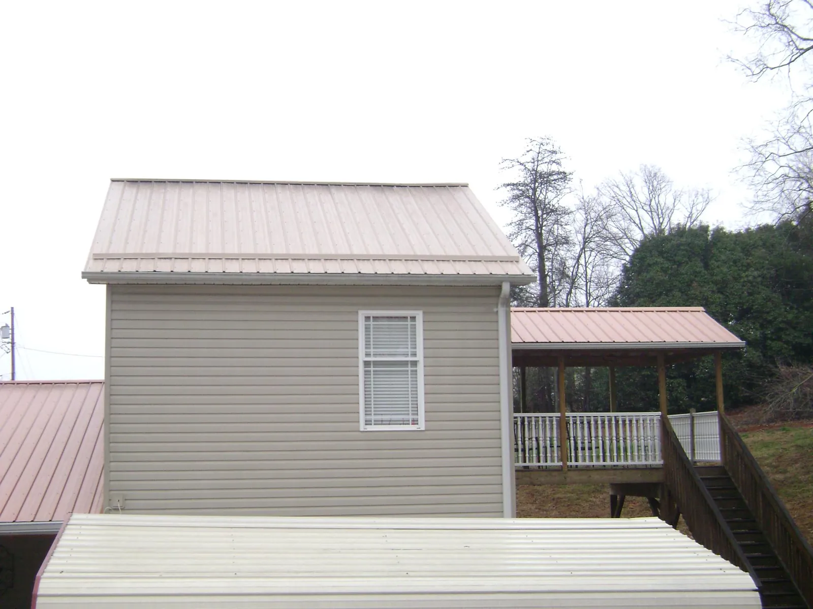 Tan metal roofs on a two story addition and attached porch, from a Roof Replacement job in Bingen