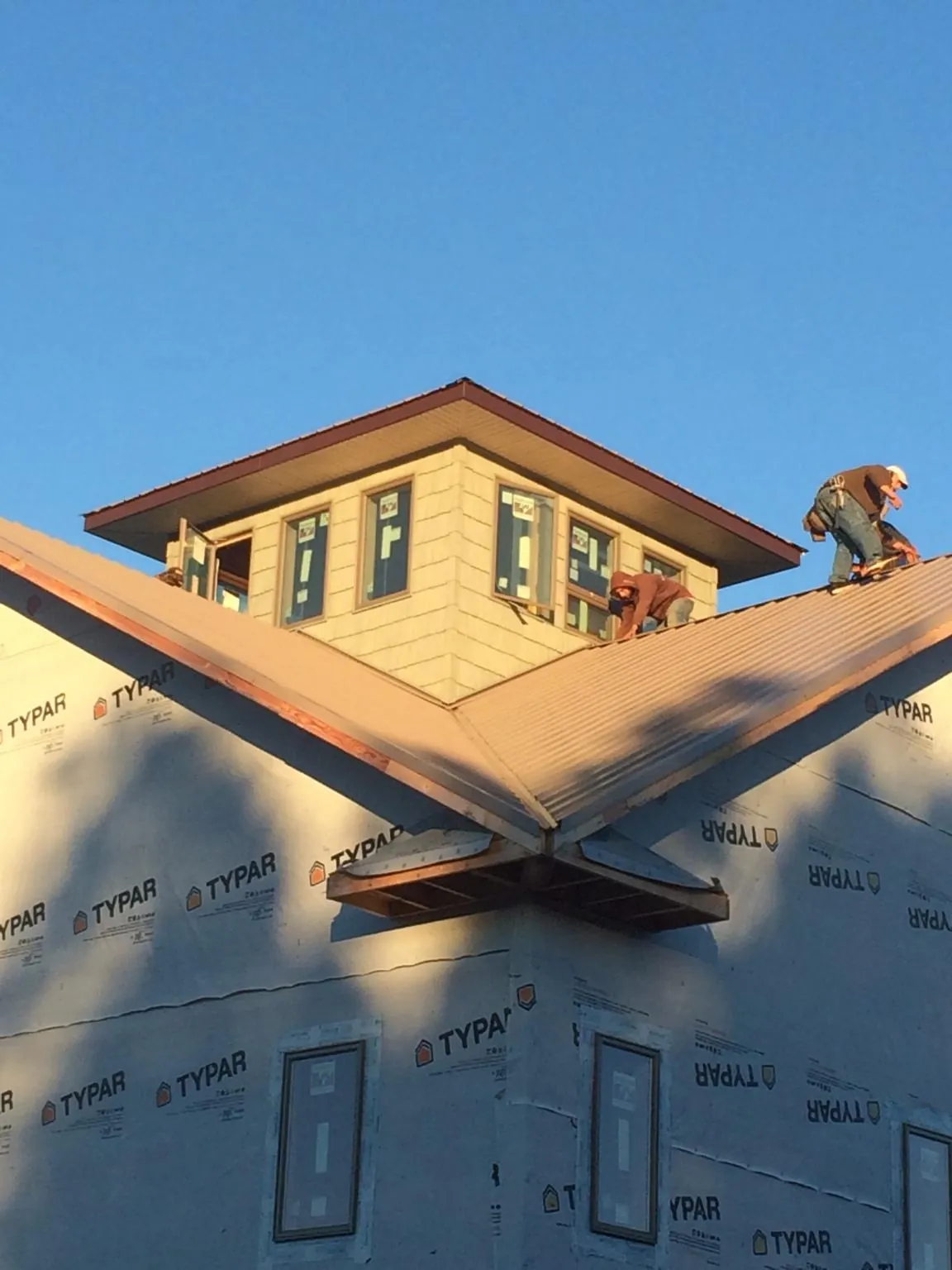 Roofers working around a rooftop cupola on a new metal roof at sunset — Roof Waterproofing in Bingen by Roofing Brothers